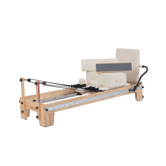 A wooden Pilates reformer machine with cream-colored foam padding, a black handlebar, and a metal guide rail, shown against a plain white background.